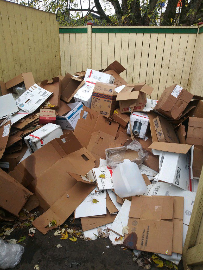 Trash Removal Seattle picking up trash from around a dumpster that's overflowing with trash