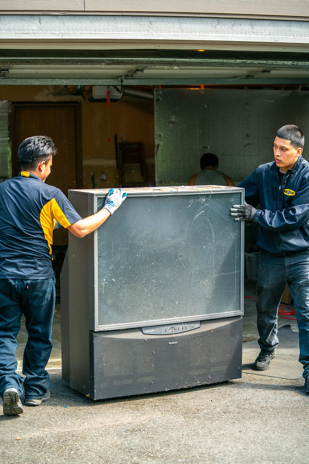 Two guys hauling a large tv removal seattle project