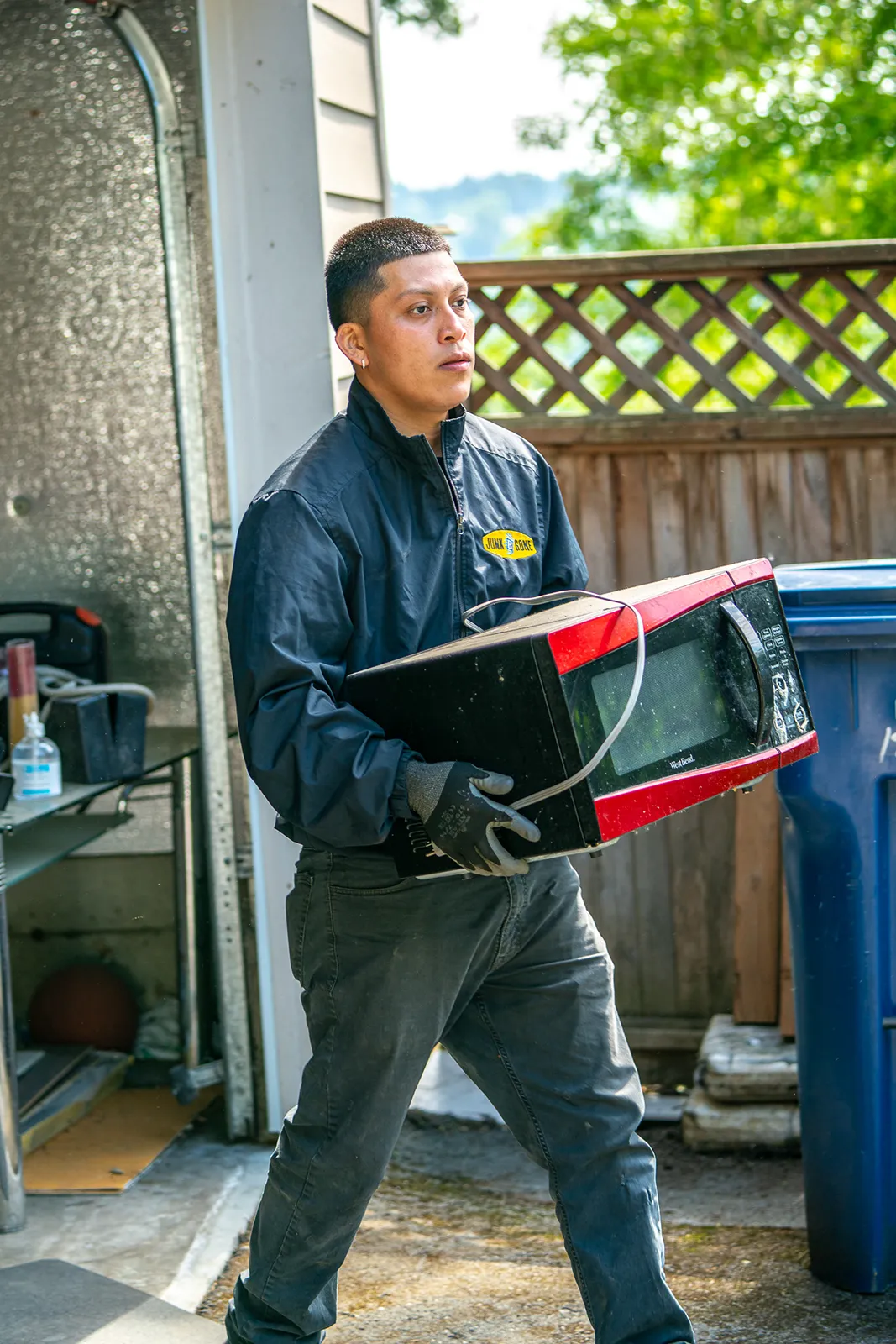 Junk B Gone employee carrying microwave during residential appliance removal