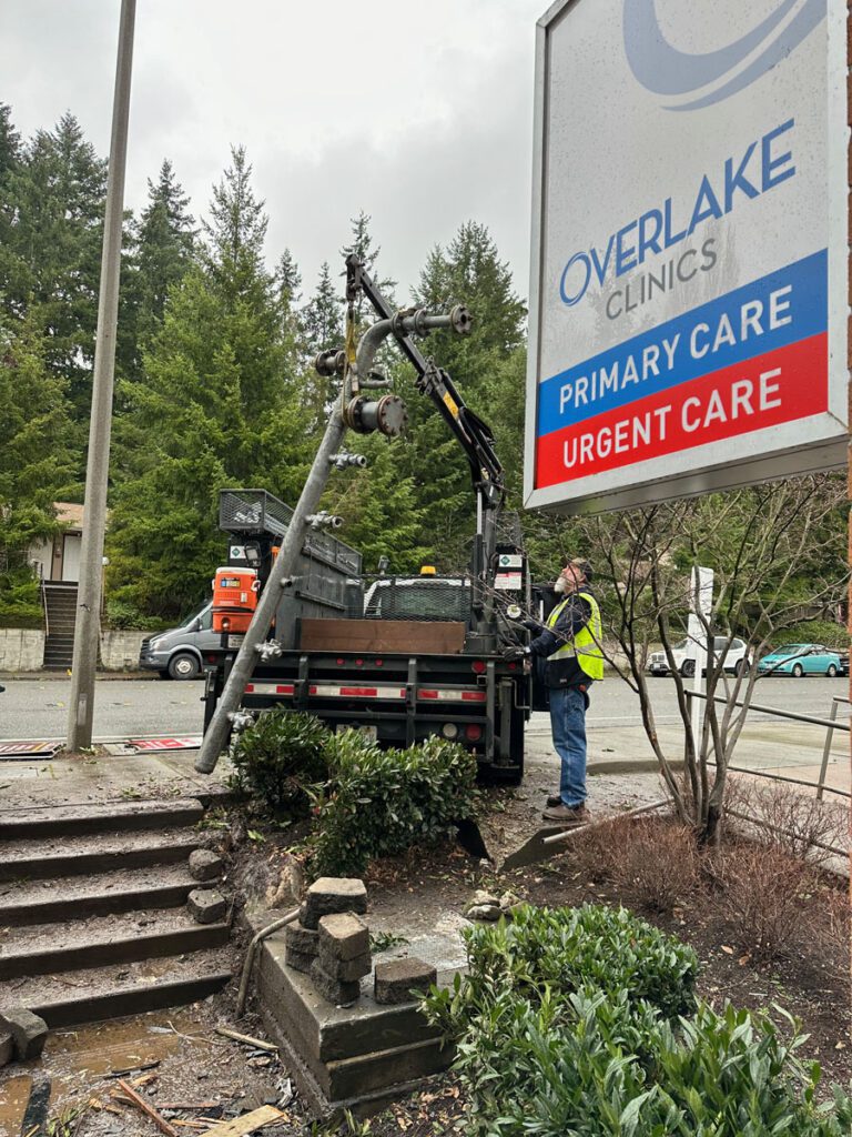 Junk B Gone crew winching the natural gas pipe into their truck next to an Overlake Clinic sign