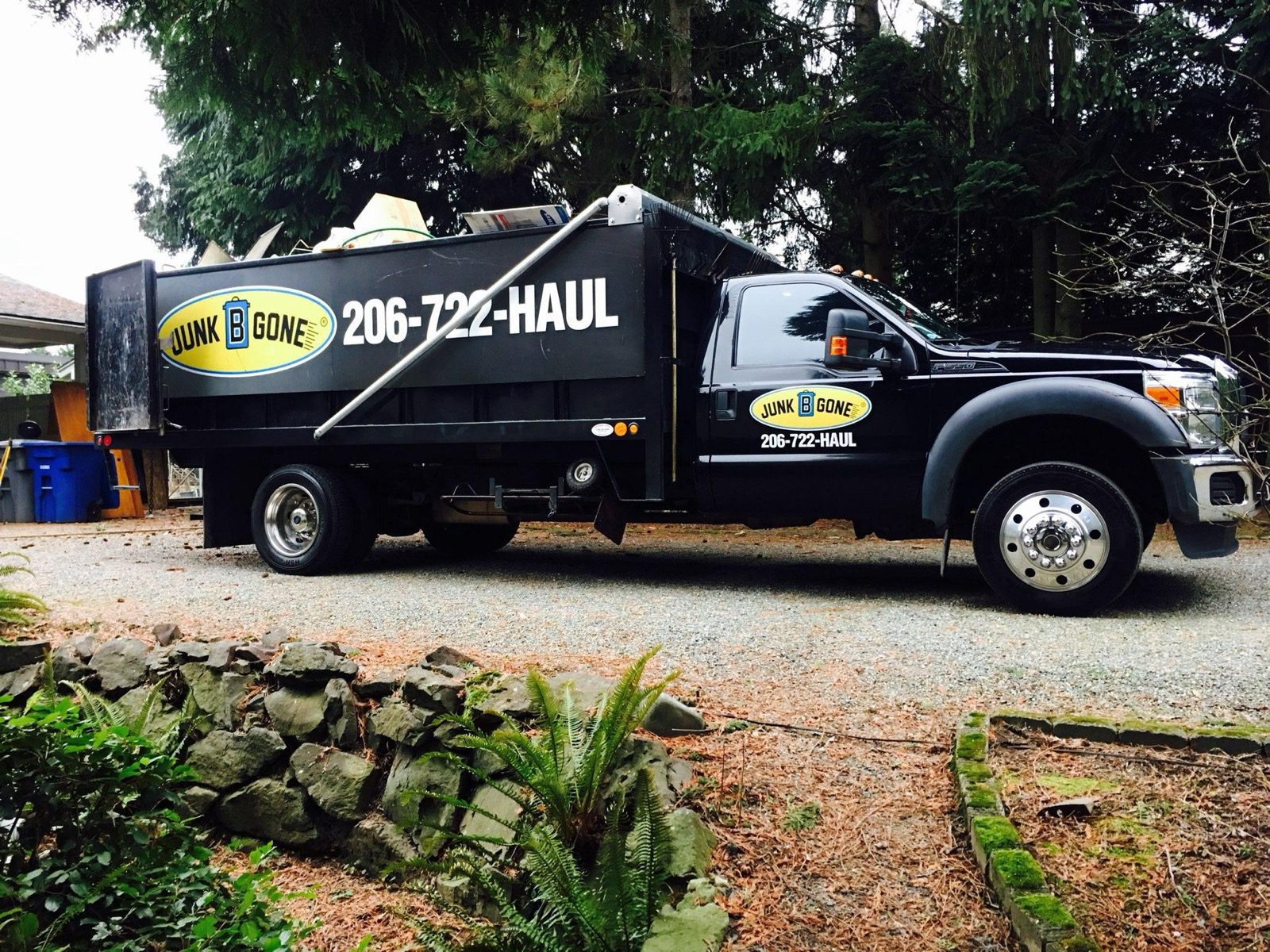 Junk B Gone branded truck — full side profile with 206-722-HAUL phone number visible, parked at a Seattle residential job