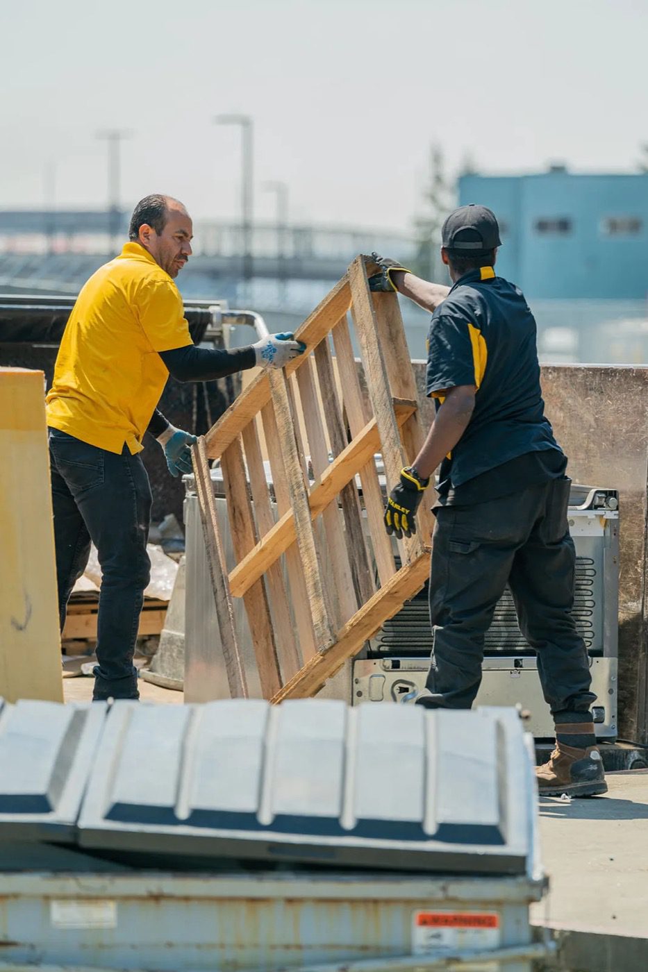 Junk B Gone crew loading a wooden pallet into the dump truck at a Seattle warehouse
