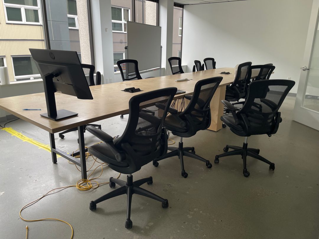 A Seattle office conference room being cleared by Junk B Gone - a large wood conference table ringed with office chairs staged for removal