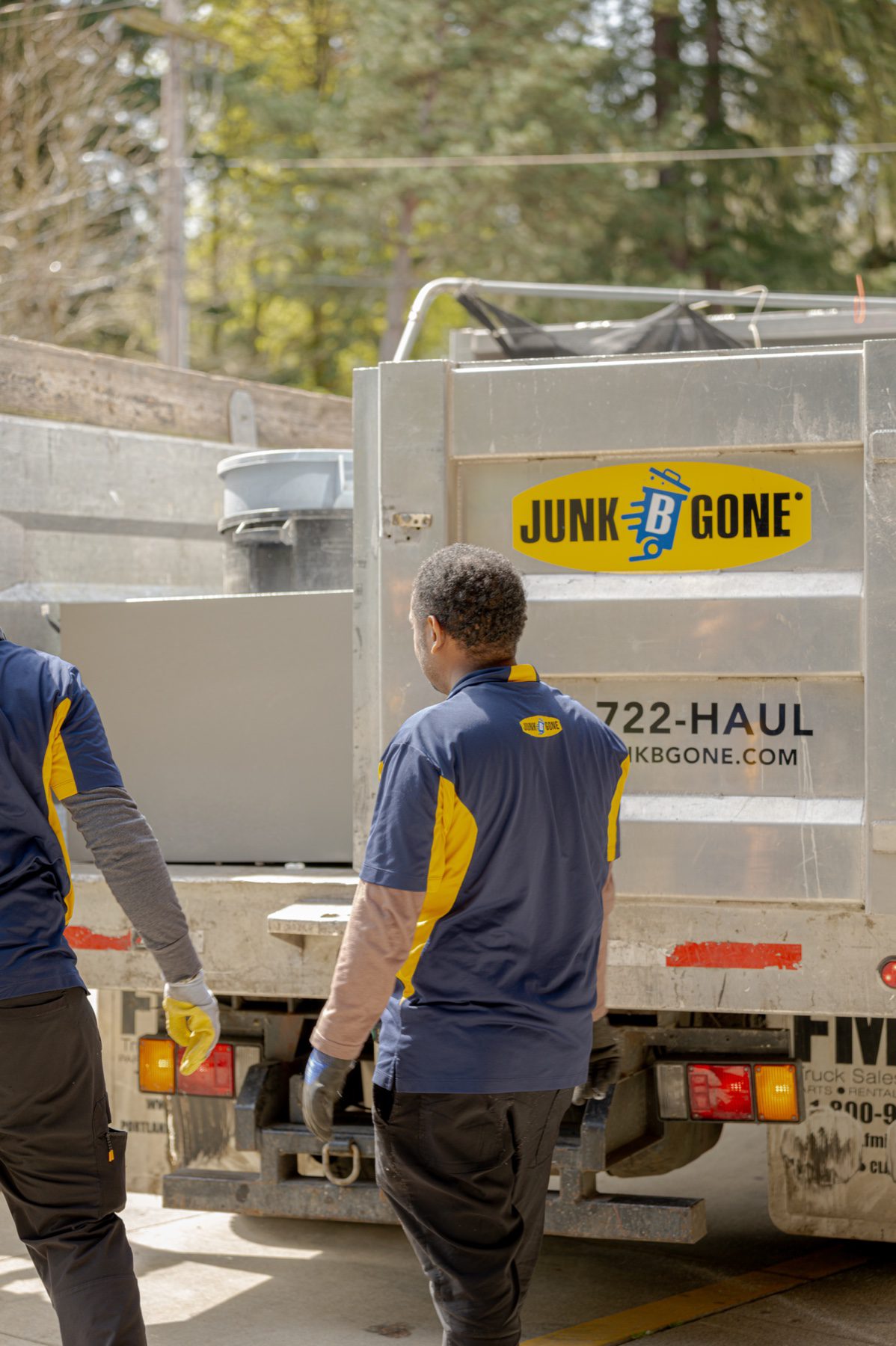 Downsizing cleanout in Seattle - two Junk B Gone crew members loading items into the branded truck