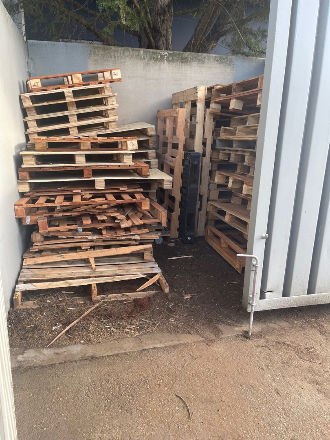 An enclosed outdoor storage area stacked with pallets, cleared by Junk B Gone in Seattle