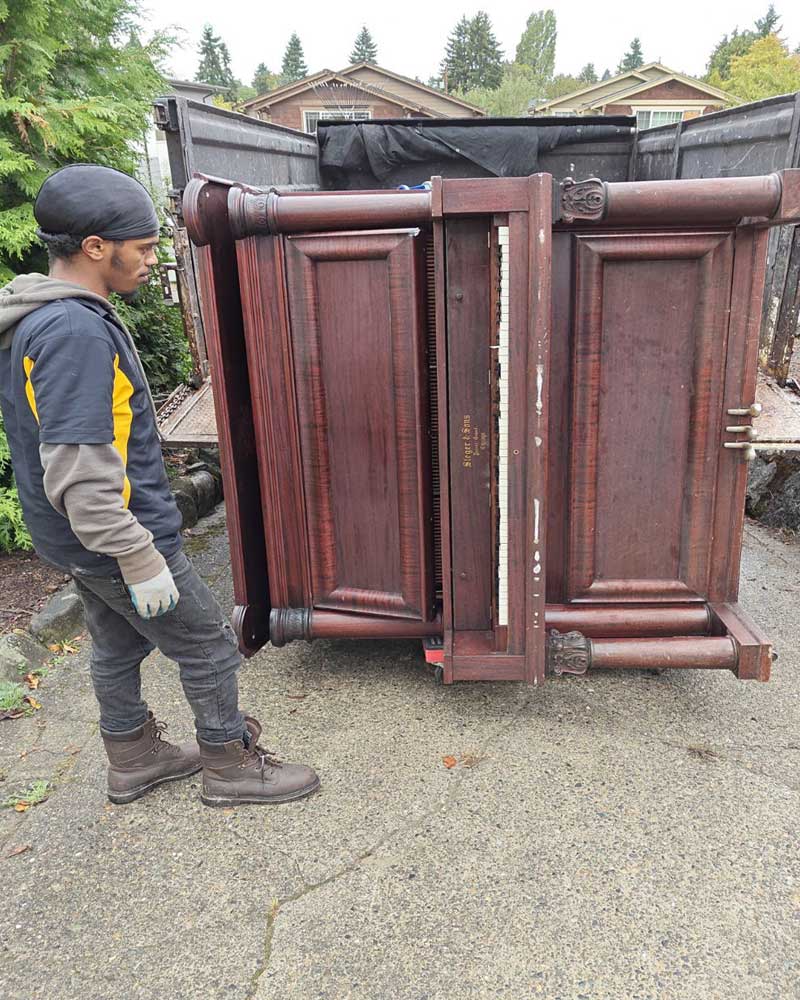 Junk removal team removing an old piano