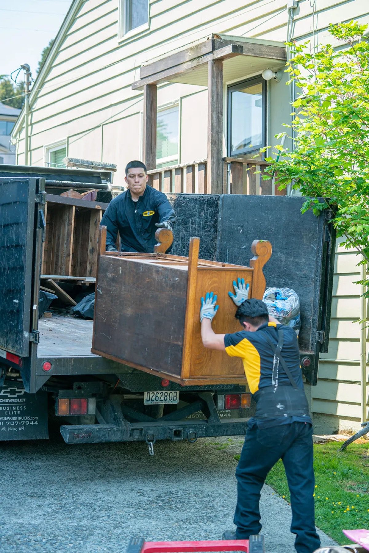 Junk B Gone crew loading a wooden dresser onto the truck