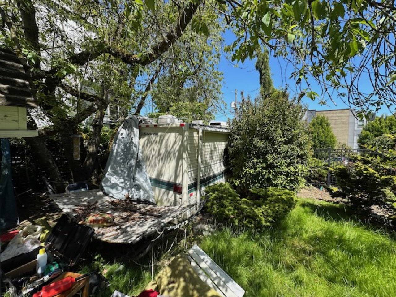Old RV stuck in a residential Seattle yard with cedars in the background