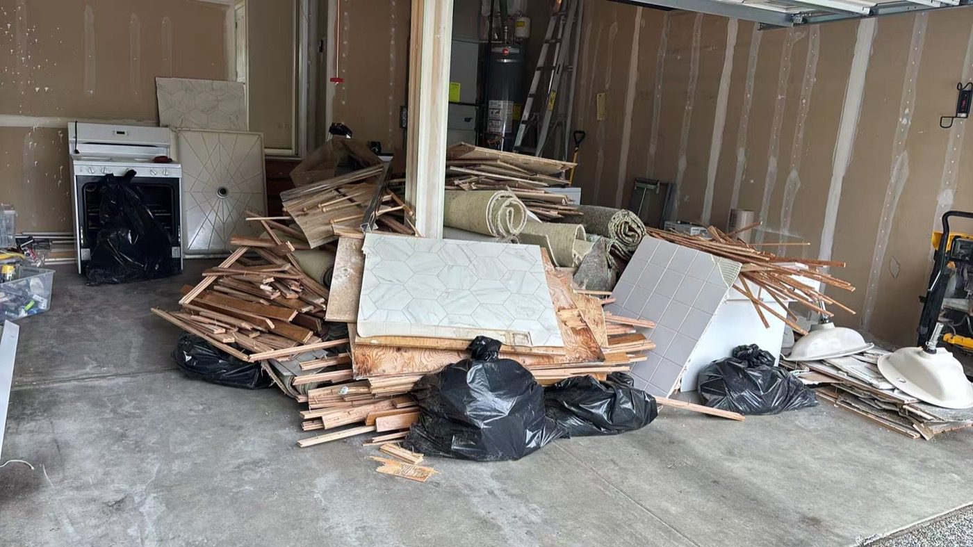Seattle garage full of renovation debris — lumber, drywall, flooring and an old appliance — cleared by Junk B Gone