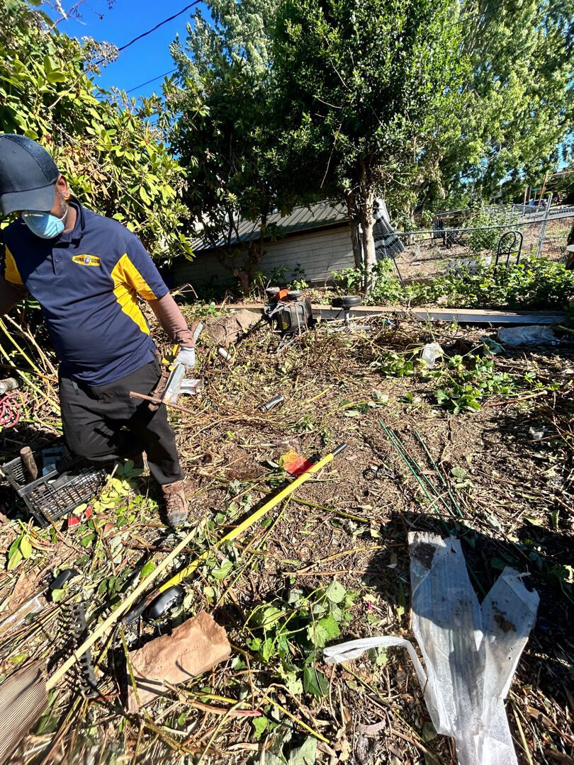 A Junk B Gone crew member clearing an overgrown Seattle backyard by hand