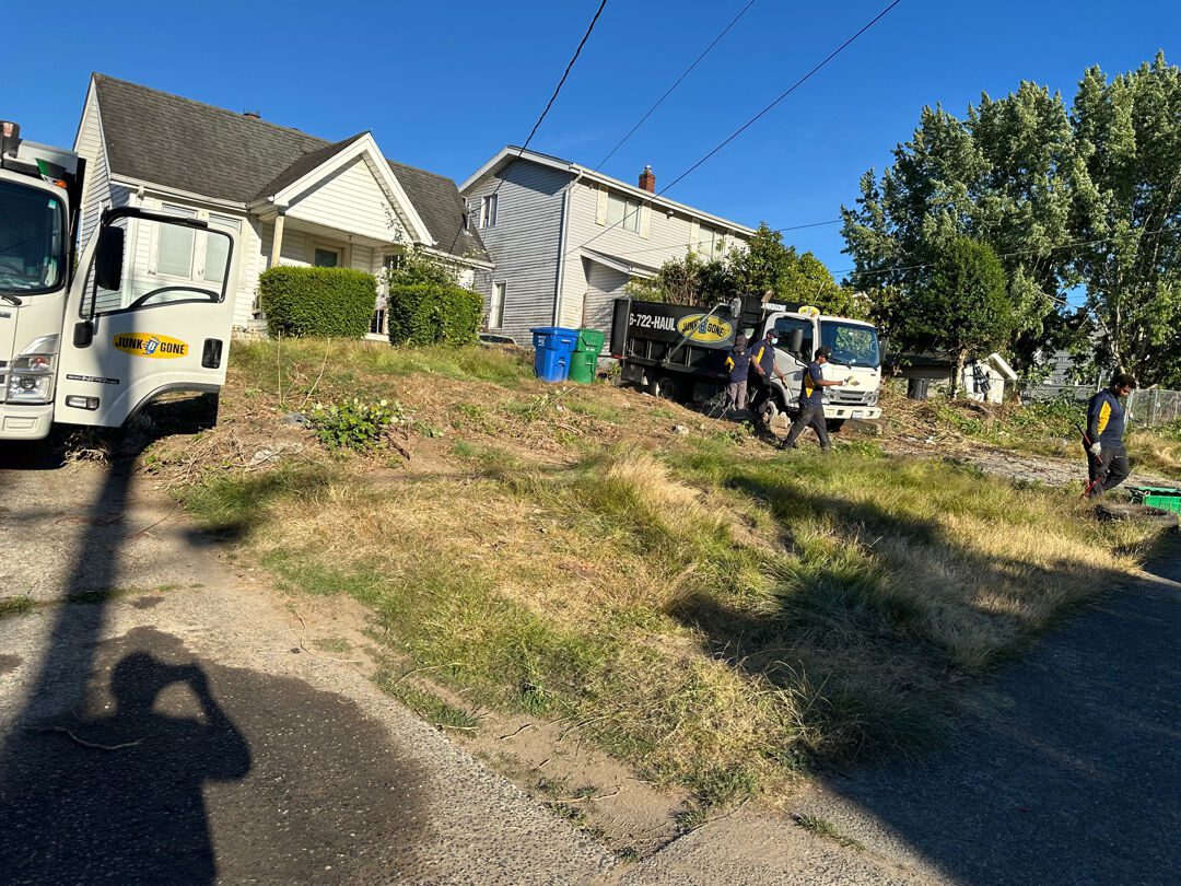 Two Junk B Gone trucks at the curb with the crew loading debris during a multi-day Seattle property cleanout